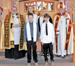 Six people in at the front of a church. Two are clergy and four are young people who have recently been confirmed.